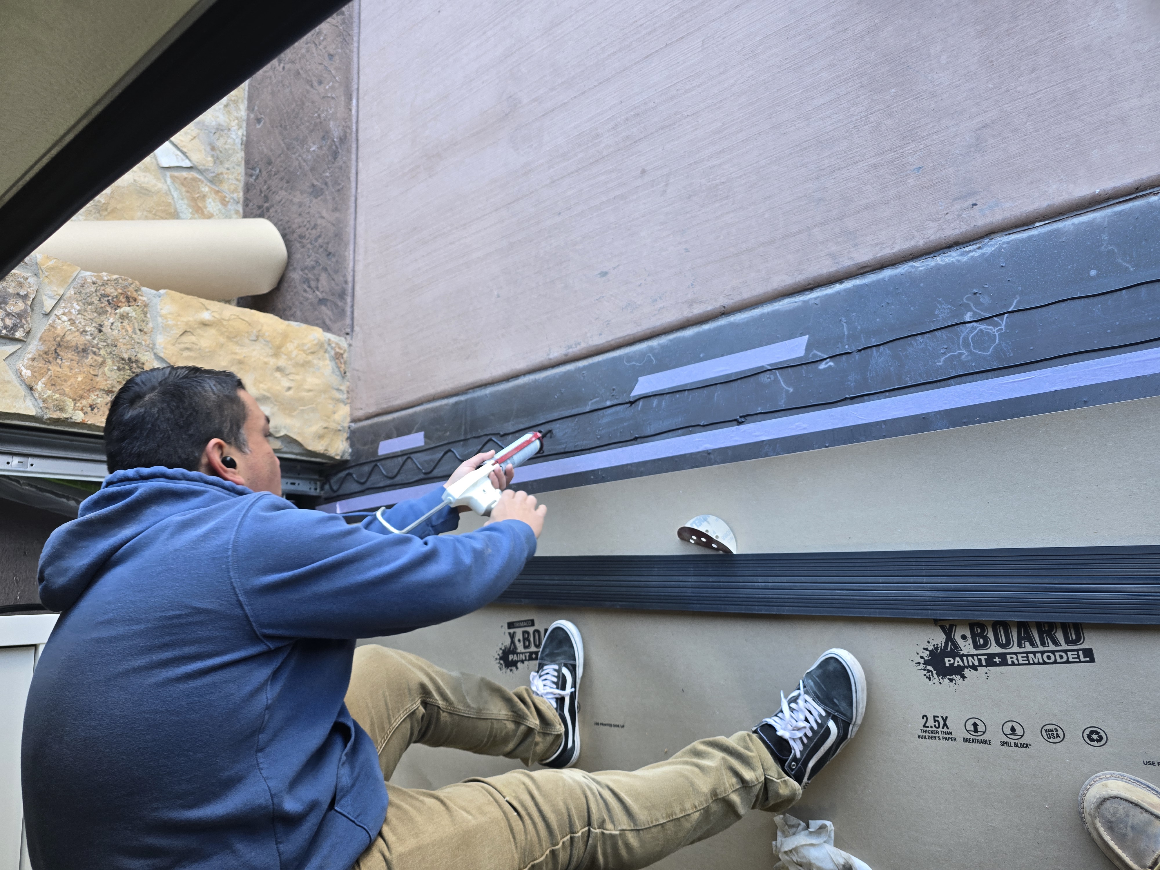 Technician sealing a garage door threshold for weather protection